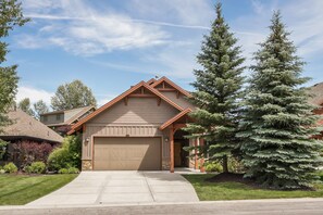 Stunning home with a gabled roof and brick facade, featuring a spacious garage and beautifully manicured lawn.