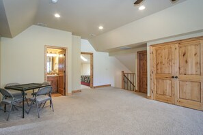 Enjoy a spacious room with a high ceiling and sloped roof design, featuring a dining area with a table and chairs, a wooden door, and a staircase leading to an upper level.