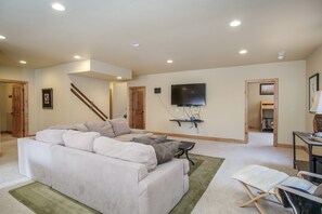 Relax in this spacious living area with a large sofa, flat-screen TV, and wooden entertainment unit.