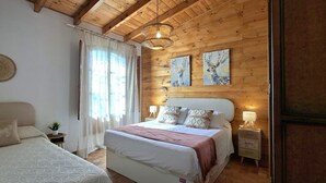 Un dormitorio con cama, mesitas de noche, lámpara, un reloj de pared y paneles de madera.