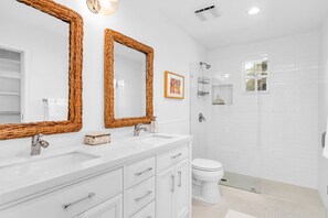 Une salle de bain moderne avec deux lavabos, des toilettes et un espace douche.