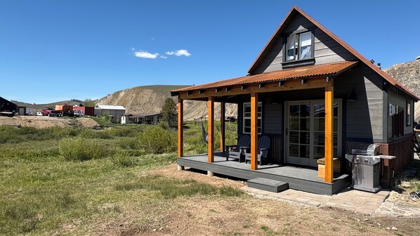 Eine kleine Hütte mit Veranda, Grill und Blick auf die umliegende Landschaft.
