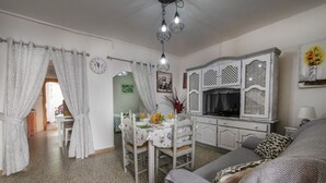 Un salon avec un canapé, une table à manger et des chaises, un coin cuisine et un escalier menant à un autre niveau.