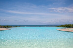 Una piscina azul cristalina con vistas al océano y una costa distante.