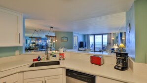 Cocina moderna con lavavajillas, un tostador rojo y cafetera. Amplia ventana con vista al océano.