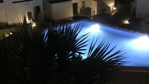 A nighttime view of a residential area with a swimming pool, white buildings, and palm trees. - fan de golf ou de quiétude cet endroit est fait pour vous  (Orihuela Costa)