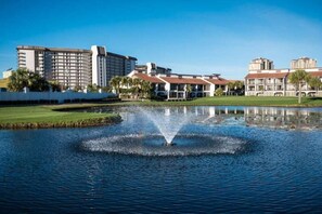 Um hotel com um edifício imponente, uma fonte em um lago e um gramado bem cuidado.