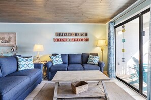 Una sala de estar con un sofá azul, una mesa de centro de madera y un letrero que dice "PRIVATE BEACH FRESH SEAFOOD".