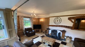 A cozy living room with a fireplace, leather sofa, and a television. - Country Cottage Sleeps 6 w/ Hot Tub & Dog-friendly (Thornhill)