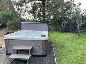 A hot tub with a cover, a small table, and a bench. - Country Cottage Sleeps 6 w/ Hot Tub & Dog-friendly (Thornhill)
