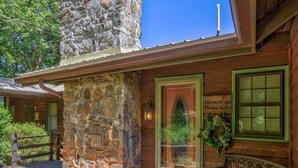 A rustic cabin with a stone exterior, a welcoming sign, and a wooden deck. - Carson's Run on Cedar Mountain--Cozy retreat with spectacular mountain views.  (Dahlonega)