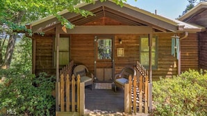 A wooden cabin with a porch, two windows, and a door. - Carson's Run on Cedar Mountain--Cozy retreat with spectacular mountain views.  (Dahlonega)
