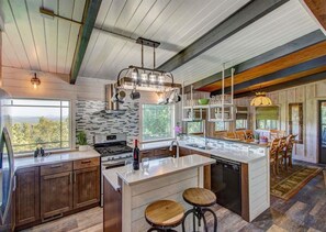 Una cocina moderna con una isla grande, taburetes de madera y vistas al exterior.