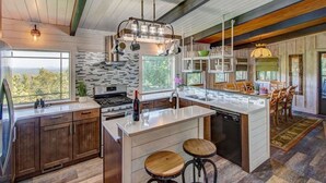 A modern kitchen with a large island, wooden bar stools, and a view of the outdoors. - Carson's Run on Cedar Mountain--Cozy retreat with spectacular mountain views.  (Dahlonega)