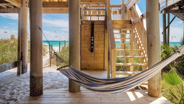 Une terrasse en bois avec un hamac, un escalier en bois et une vue sur la plage.
