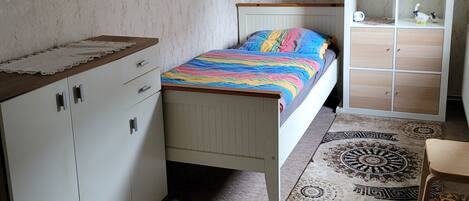 A bedroom with a bed, a wardrobe, a desk, and a cabinet.