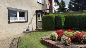 A house with a well-maintained garden, a satellite dish, and neatly trimmed hedges.