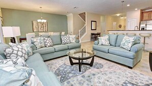 A living room with two light blue sofas, a glass coffee table, and patterned rugs. - 8BR ChampionsGate | Cinema, Arcade & Private Pool (Davenport)
