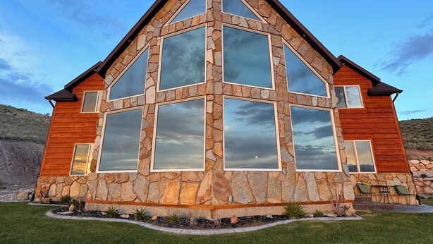 Une maison moderne avec une façade en pierre, de grandes fenêtres et une pelouse bien entretenue.