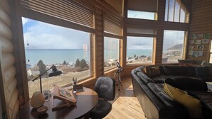 Un chalet confortable avec de grandes fenêtres donnant sur la mer et une plage.