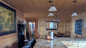 Un intérieur en bois avec un long comptoir, des fauteuils en cuir et des luminaires suspendus.