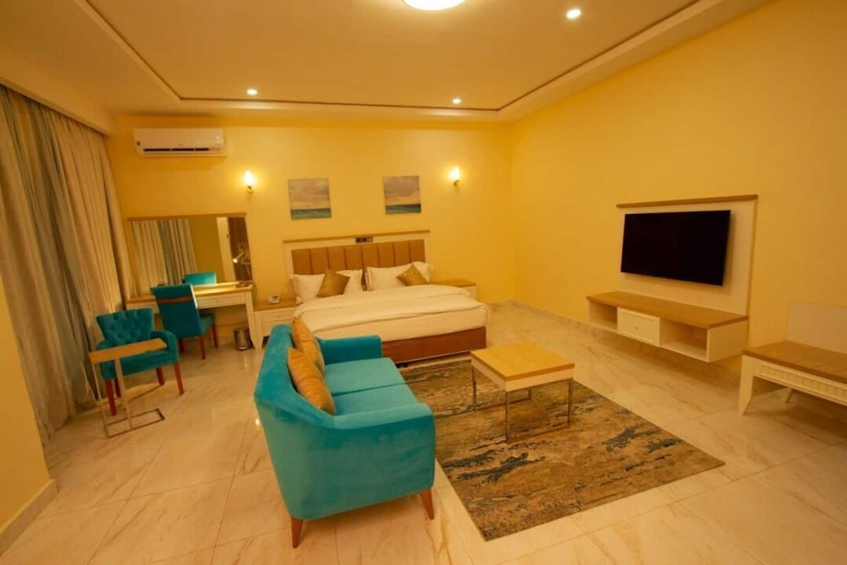 Una habitación de hotel con cama, televisor, escritorio y sofá.