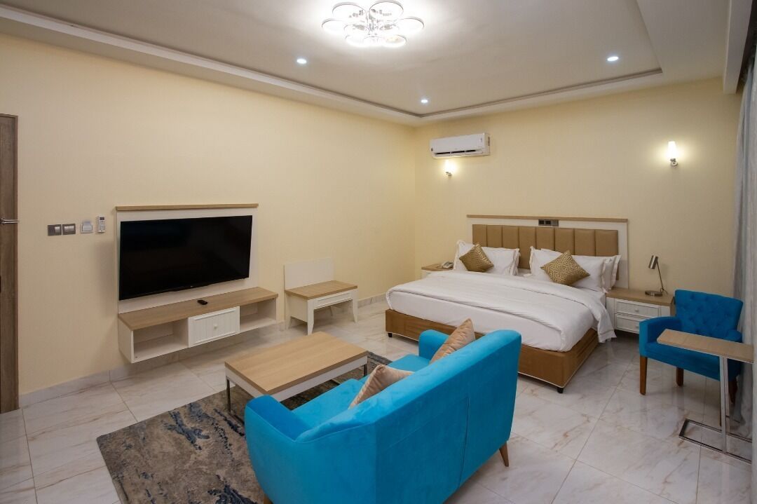 Una habitación de hotel moderna con una cama grande, un televisor de pantalla plana, un sofá y una mesa de centro.