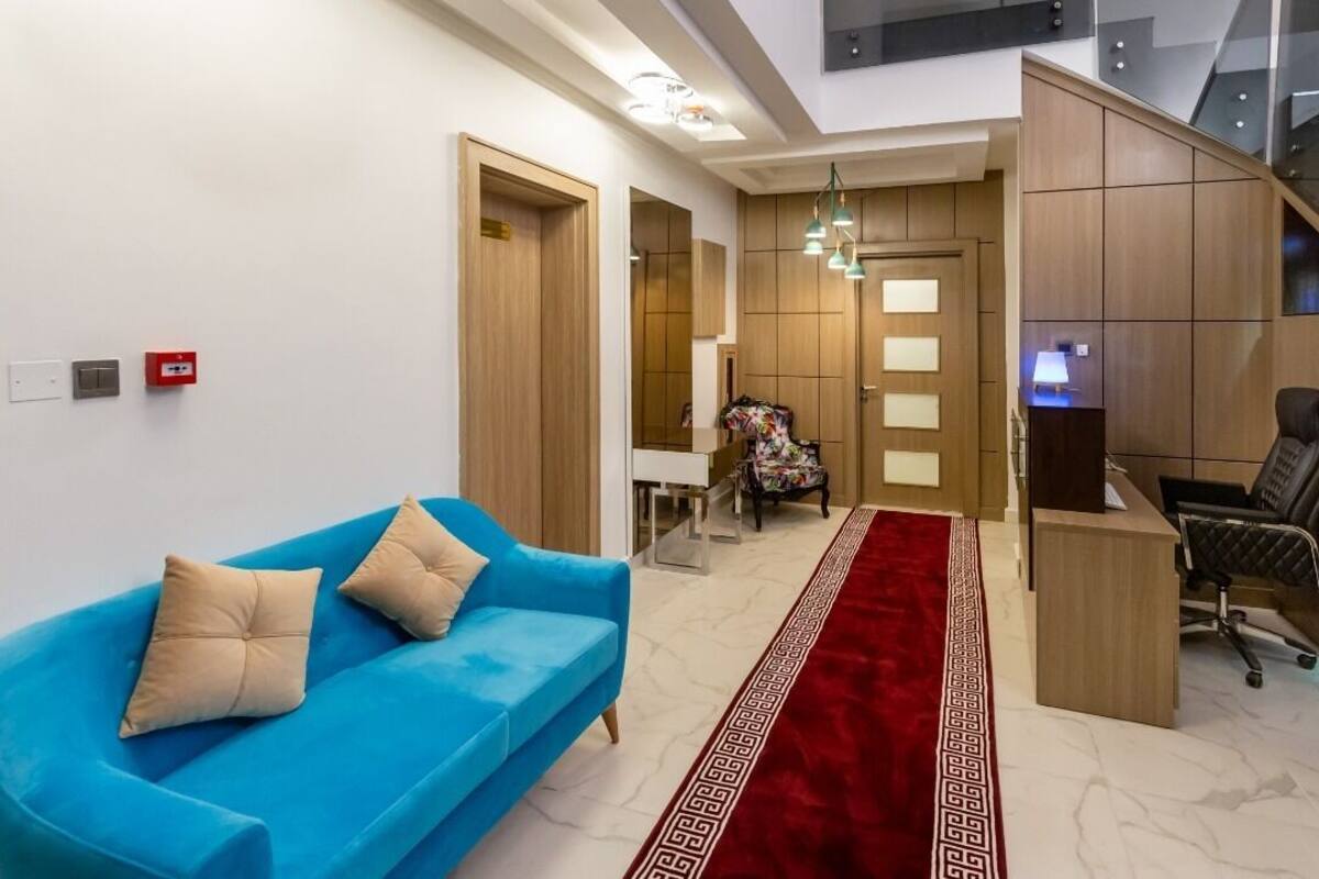 Un moderno vestíbulo de hotel con un sofá azul, una alfombra roja y un mostrador de recepción.