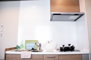 Een koelkast, een magnetron, een kookplaat, kookgerei, borden en bestek