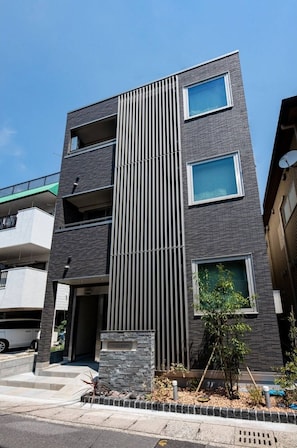 Stylish building with a central column, offering multiple windows and a small garden area.