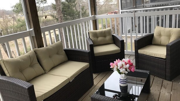 A covered outdoor seating area with wicker furniture and cushions, a glass coffee table, and a vase with flowers. - Spacious 4 Bed, 4,5 bath. Pet friendly. Come enjoy Rehoboth! (Rehoboth Beach)