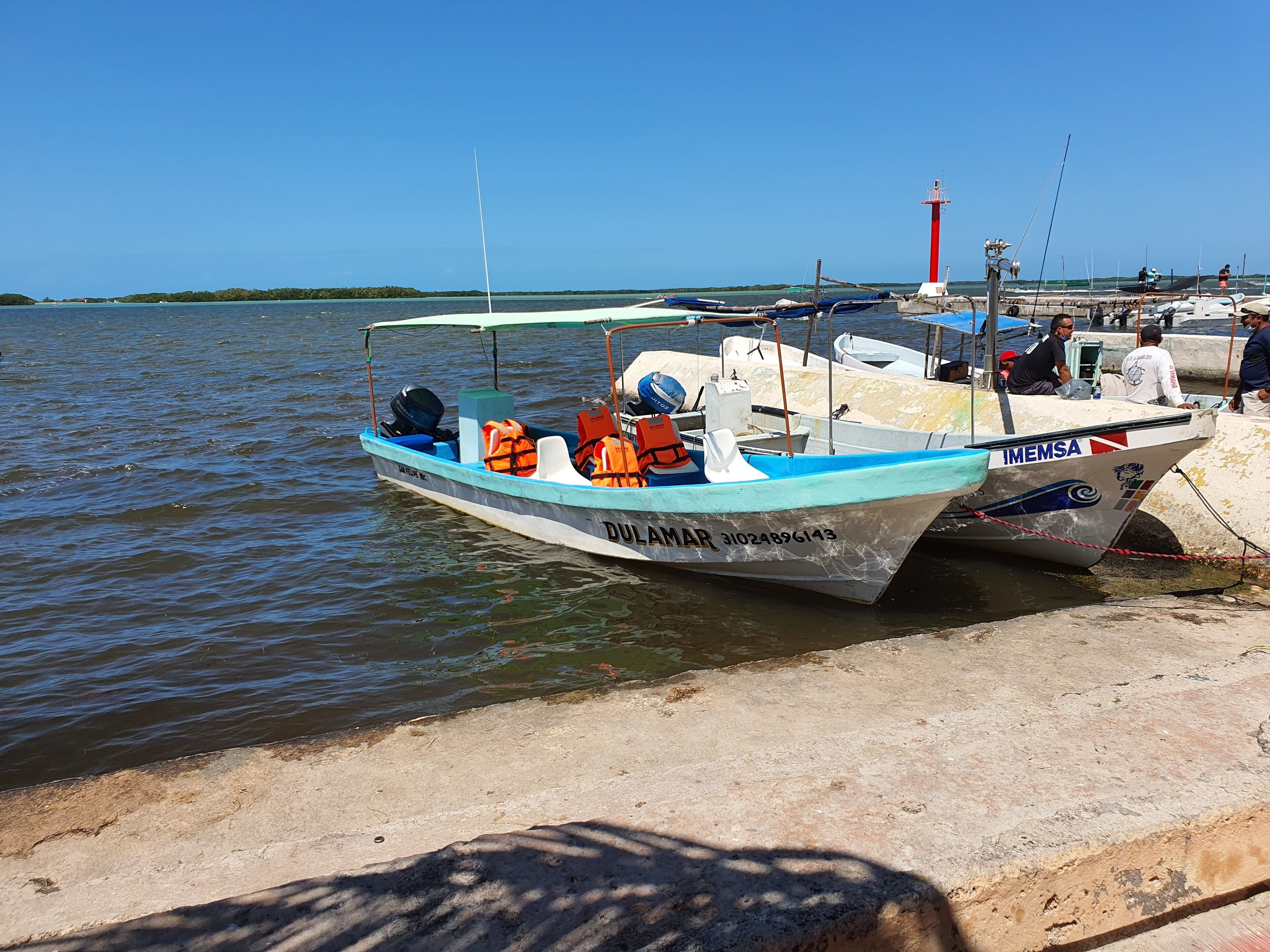 A boat docked at a pier with a lighthouse in the background.