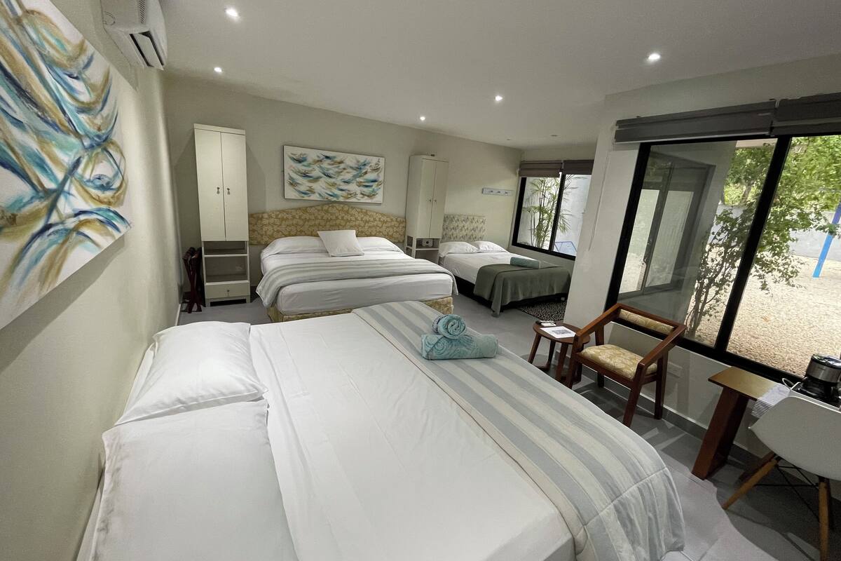 Une chambre d’hôtel avec deux lits, un bureau et une chaise. Il y a une fenêtre donnant sur un paysage verdoyant.