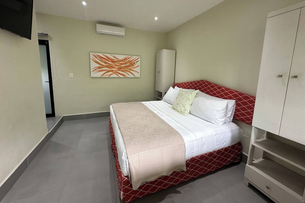 Une chambre à coucher avec un lit, une armoire, un climatiseur et un tableau accroché au mur.