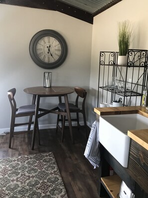 Cozy kitchen area with a round wall clock, dining table, and potted plant.