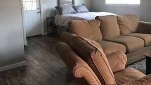 Une pièce spacieuse avec un grand canapé marron, un tapis à motifs et un ventilateur de plafond.