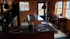 Une cuisine dotée de meubles en bois, d’une cuisinière, d’un évier et d’un coin repas avec une table et des chaises.