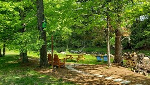 Un espace pique-nique avec des bancs en bois et une table à pique-nique, le tout entouré d’arbres.