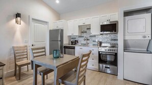 Una cocina moderna con armarios blancos, un refrigerador de acero inoxidable, un microondas, una estufa y un lavavajillas.