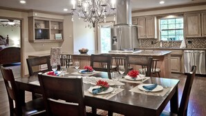 A modern kitchen with a dining area set for six. It includes a chandelier, stainless steel appliances, and a view of the outdoors. - Rural Beauty with Urban Convenience (Hot Springs)