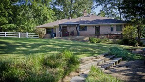 A two-story house with a covered porch, a brick exterior, and a well-maintained lawn. - Rural Beauty with Urban Convenience (Hot Springs)