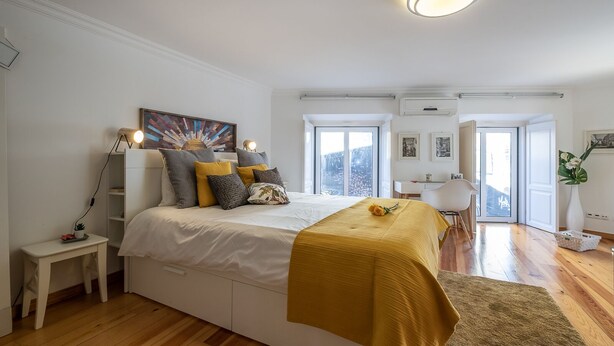 A modern bedroom with a bed, bedside table, and a view of the outside.