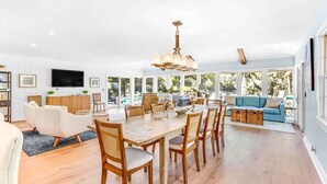 A spacious living area with a dining table, chairs, a sofa, and a TV mounted on the wall. - Exquisite Home w/ Private Pool & Dock Hilton Head (Hilton Head Island)