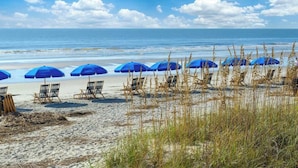 A beach with blue umbrellas and lounge chairs. - Exquisite Home w/ Private Pool & Dock Hilton Head (Hilton Head Island)