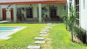 A building with a tiled roof, a swimming pool, and a stone pathway leading to the entrance. - Hotel Plaza Matamoros (Matamoros)