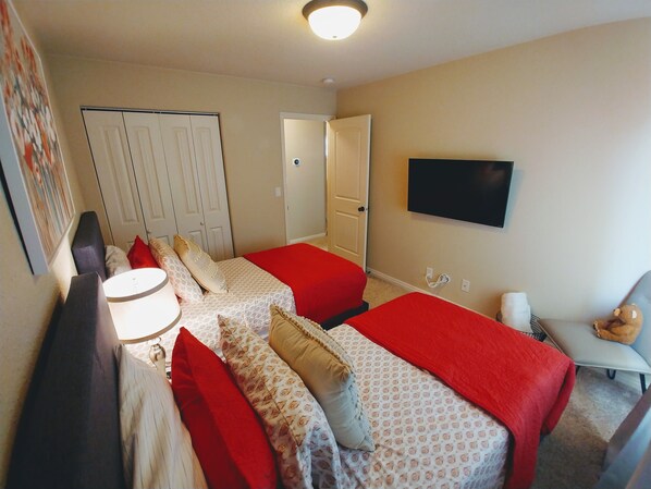 A hotel room with two beds, a TV, a desk, and a chair.