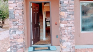 A house entrance with a stone pillar, a door, and a mailbox. - The Happy Cactus Home (Kanab)