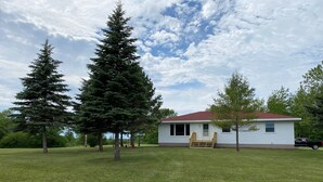 A single-story house with a red roof, a front porch, and a small deck.