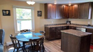 A kitchen with a dining table, wooden cabinets, and a built-in island.