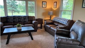 A living room with two leather sofas, a coffee table, a side table with a lamp, and framed pictures on the wall.